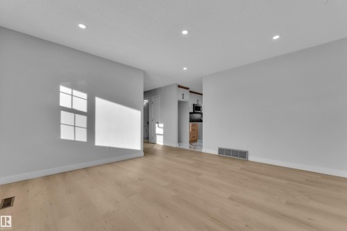 Light wood-finish flooring with recessed ceiling lighting - 5118 17A Avenue Nw, Edmonton, AB - Indoor Photo Showing Other Room