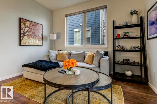 Bright living area featuring wood-finish flooring, a large window, and light-toned walls - 67 603 Watt Boulevard, Edmonton, AB - Indoor