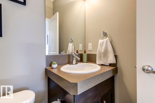 Corner vanity with an integrated sink, polished chrome faucet, full-width mirror, and dark wood-finish cabinetry - 67 603 Watt Boulevard, Edmonton, AB - Indoor Photo Showing Bathroom