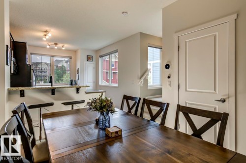 Dining area featuring a wood-finish dining table and direct sightlines to the kitchen pass-through with a granite-look countertop - 67 603 Watt Boulevard, Edmonton, AB - Indoor Photo Showing Dining Room