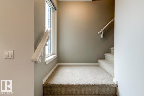 Carpeted staircase featuring a window and painted handrail - 67 603 Watt Boulevard, Edmonton, AB - Indoor Photo Showing Other Room