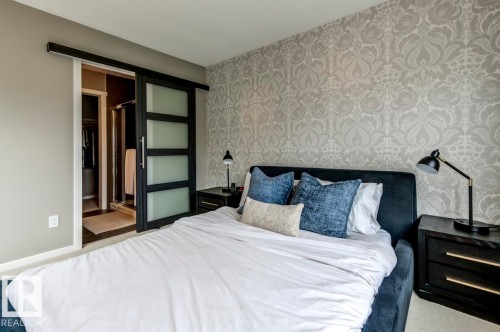 Bedroom featuring patterned wallpaper, neutral wall tones, and carpet flooring - 67 603 Watt Boulevard, Edmonton, AB - Indoor Photo Showing Bedroom