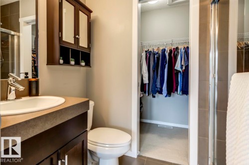 Bathroom featuring a dark wood-finish vanity with an undermount sink, a coordinating wall-mounted mirrored medicine cabinet, a standard toilet, and a glass-enclosed shower - 67 603 Watt Boulevard, Edmonton, AB - Indoor Photo Showing Bathroom
