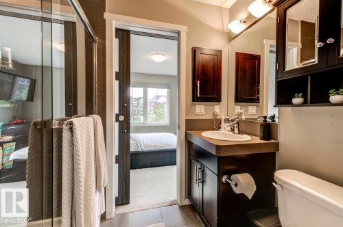 Bathroom featuring a dark wood-finish vanity with an undermount sink, a large wall-mounted mirror, and a coordinated dark wood-finish medicine cabinet - 67 603 Watt Boulevard, Edmonton, AB - Indoor Photo Showing Bathroom