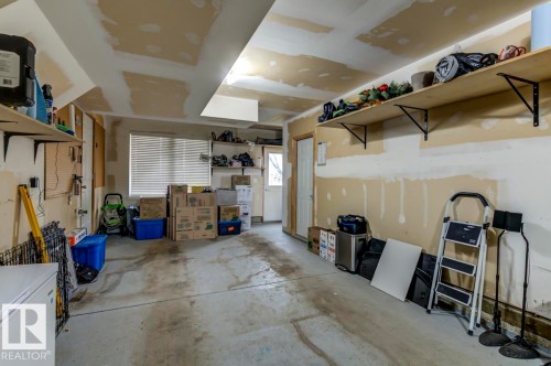 Spacious garage with exposed drywall, concrete flooring, and multiple built-in storage shelves - 67 603 Watt Boulevard, Edmonton, AB - Indoor Photo Showing Garage