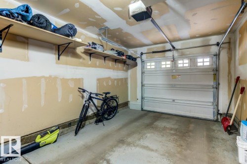 Single-bay garage featuring a sectional overhead door with upper window inserts and an automatic opener - 67 603 Watt Boulevard, Edmonton, AB - Indoor Photo Showing Garage