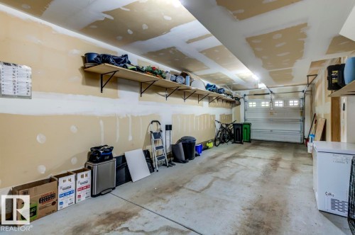 Spacious garage featuring a concrete floor, overhead lighting, and built-in shelving units - 67 603 Watt Boulevard, Edmonton, AB - Indoor Photo Showing Garage