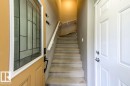 Entryway featuring a decorative glass panel door with a dark bronze handle, a carpeted staircase with a white handrail, and a paneled interior door with chrome hardware - 67 603 Watt Boulevard, Edmonton, AB  - Indoor Photo Showing Other Room 