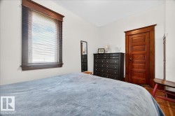 White wall paint, window with wood-finish blinds, wood-finish trim, wood-finish paneled door, and wood-finish flooring - 