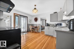 Bright kitchen featuring hardwood flooring, light gray cabinetry, and stone countertops - 