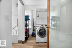 Dedicated laundry area featuring a stacked washer and dryer, wood-finish flooring, and a window with blinds - 