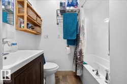 Bathroom featuring a white vanity with an integrated sink, chrome faucet, and wood-finish flooring - 