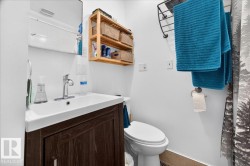 Bathroom featuring a dark wood-finish vanity with an integrated sink, polished chrome faucet, built-in medicine cabinet, and a wall-mounted wooden shelving unit - 