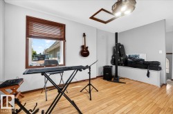 Bright room featuring wood-finish flooring, a large window with wooden blinds, and a built-in window bench - 
