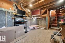 Basement space featuring exposed wood beam ceiling, concrete foundation walls, and a spiral staircase with wood treads and a metal railing - 
