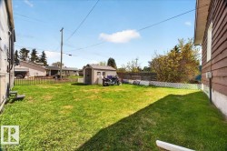 Expansive green lawn with a white lattice fence and a utility shed - 