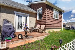 Rear deck with double glass-panel doors, textured stucco siding, and horizontal wood plank siding - 