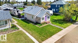 Front yard featuring a manicured lawn, concrete walkway with lighting, and a vibrant purple entry door - 