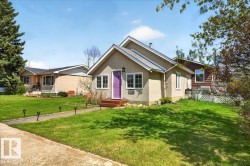 Stucco exterior with a peaked roofline, vibrant purple entry door, white window frames, and a concrete walkway - 