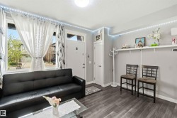 Living area featuring wood-finish flooring, a full-lite entry door, and a prominent window - 