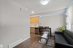 Open-concept living area with wood-finish flooring, recessed lighting, and a window with curtains - 