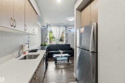 Compact kitchen area featuring wood-finish cabinetry, a stainless steel sink, and light-toned countertops - 