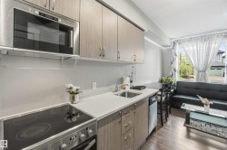 Compact kitchen featuring wood-finish cabinetry, stainless steel microwave, and an electric range with a black cooktop - 