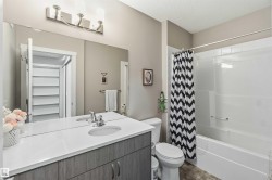 Bathroom featuring a single vanity with a white countertop, chrome fixtures, and wood-finish cabinetry - 