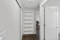 Hallway featuring a built-in shelving unit, a white barn door, and wood-finish flooring - 