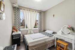 Bedroom featuring a large window, neutral wall paint, wood-finish flooring, and a ceiling light fixture - 