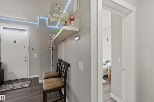 Entryway featuring a white door with transom window, wood-finish flooring, and a wall-mounted shelf with integrated coat hooks - 456 Allard Boulevard, Edmonton, AB - Indoor Photo Showing Other Room