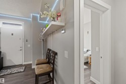 Entryway featuring a white door with transom window, wood-finish flooring, and a wall-mounted shelf with integrated coat hooks - 
