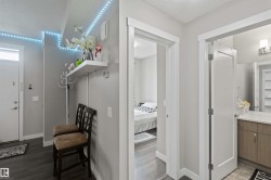 Entryway featuring wood-finish flooring, a white floating shelf, and contemporary light grey walls - 