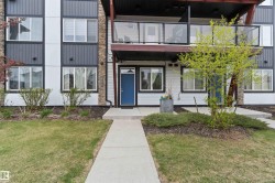 Multi-level exterior featuring white siding, dark grey vertical panels, and stone accents - 