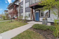Contemporary exterior featuring white siding, dark trim, a vibrant blue entry door, and stone accents - 