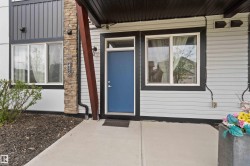 Blue entry door with transom window, framed by light-colored siding and a stone veneer column - 