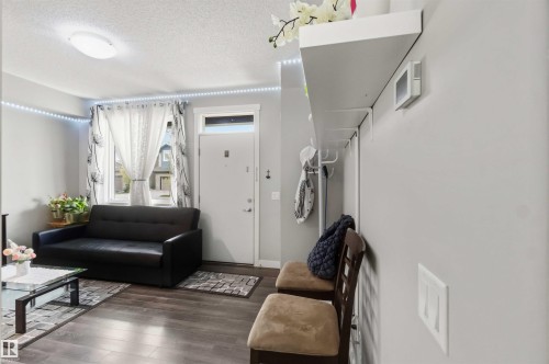 Entryway area featuring wood-finish flooring, a white entry door with frosted glass transom, and an overhead lighting fixture - 456 Allard Boulevard, Edmonton, AB - Indoor Photo Showing Living Room