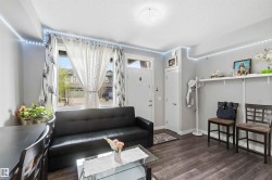 Living area featuring wood-finish flooring, a front entry door, a window with exterior views, and a built-in wall shelf - 