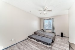 Room featuring wood-finish flooring, a window with curtains, and a ceiling fan with integrated lighting - 