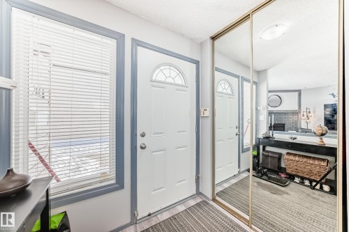 Entryway featuring light wood-finish flooring, a white door with an arched glass insert, and a window with white horizontal blinds - 214A Warwick Road, Edmonton, AB - Indoor Photo Showing Other Room