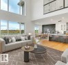 Spacious living area featuring a two-story ceiling, large windows, and wood-finish flooring - 13032 186 Avenue, Edmonton, AB  - Indoor Photo Showing Living Room 