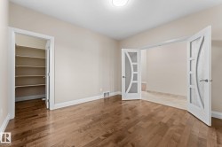 Hardwood-finish flooring extending through the room, complemented by a built-in closet with multiple shelves - 