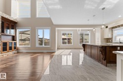 Open-concept living space featuring high ceilings and a blend of wood-finish flooring and large format tile - 