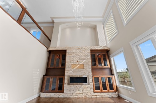 Two-story living area featuring a stone-clad fireplace with a built-in linear electric insert and integrated wood-finish cabinetry - 16543 132 Street, Edmonton, AB - Indoor Photo Showing Other Room