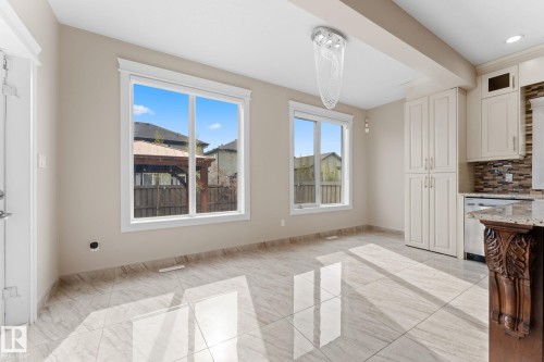 Open-concept dining area featuring large windows, high-gloss tile flooring, and an elegant chandelier - 16543 132 Street, Edmonton, AB - Indoor Photo Showing Other Room