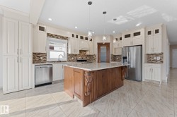 Expansive kitchen featuring a large central island with carved wood detailing and a stone-finish countertop - 