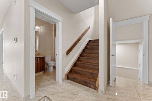 Rich wood staircase featuring a coordinating handrail and white trim - 16543 132 Street, Edmonton, AB - Indoor Photo Showing Other Room