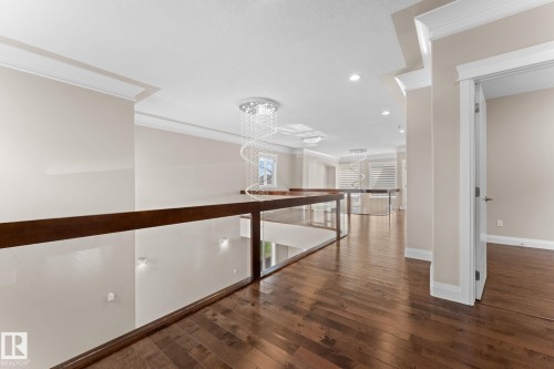 Hardwood flooring extends throughout this upper-level hallway, featuring a glass and wood railing - 16543 132 Street, Edmonton, AB - Indoor Photo Showing Other Room