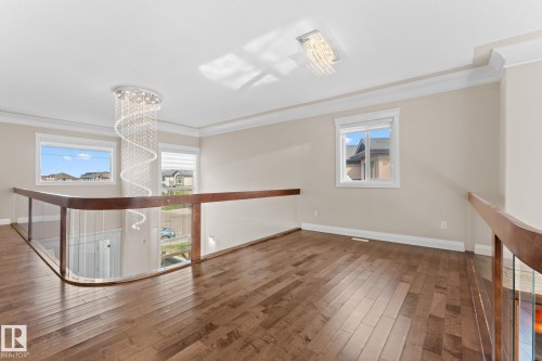 Upper-level landing featuring wood-finish flooring and a curved glass railing system - 16543 132 Street, Edmonton, AB - Indoor Photo Showing Other Room