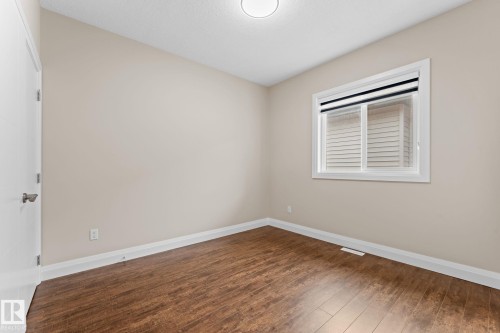 Interior room featuring wood-finish flooring, light-toned walls, and a white-framed window - 16543 132 Street, Edmonton, AB - Indoor Photo Showing Other Room